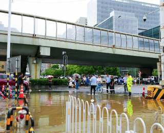 暴雨中的武汉大学珞珈门：家长互助趟渍水，城管拉绳筑 “安全线”